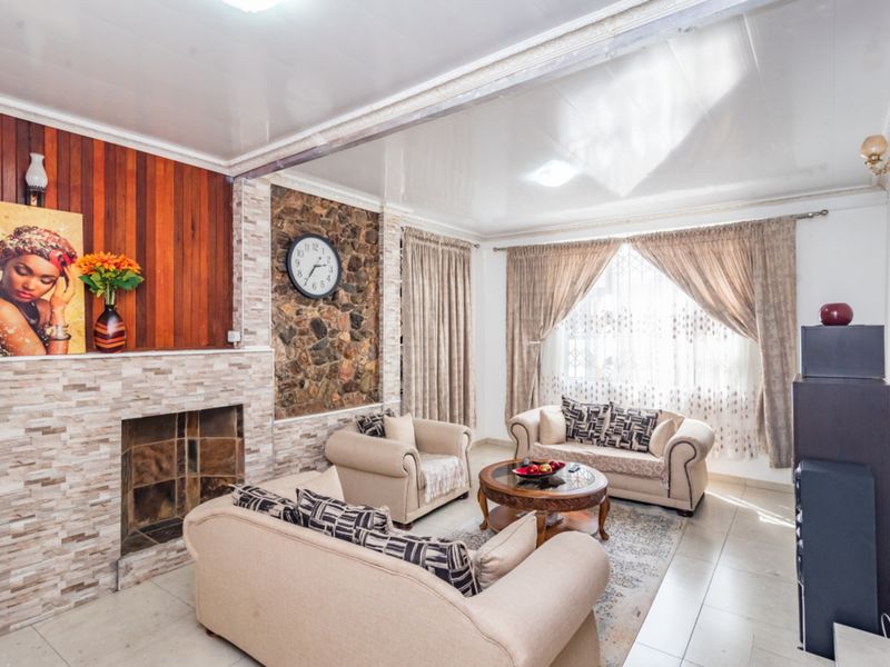 A living room featuring a stone fireplace, wood-paneled accent wall, tiled flooring, and decorative ceiling molding.