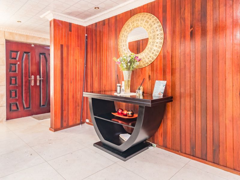 Entrance foyer featuring warm wood wall paneling, tiled flooring, and a double door entry with decorative ceiling detailing.