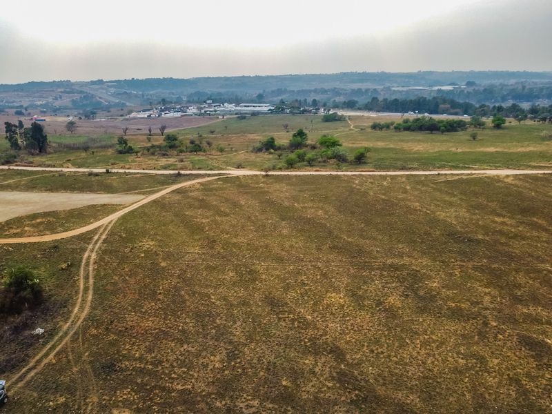 An aerial view of a large, undeveloped residential plot featuring natural terrain and dirt access tracks with surrounding landscape views.