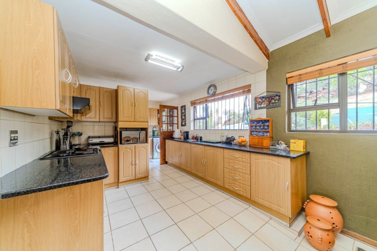 Spacious kitchen featuring laminate cabinetry, granite countertops, built-in oven, gas hob, and tiled flooring with exposed timber beams.