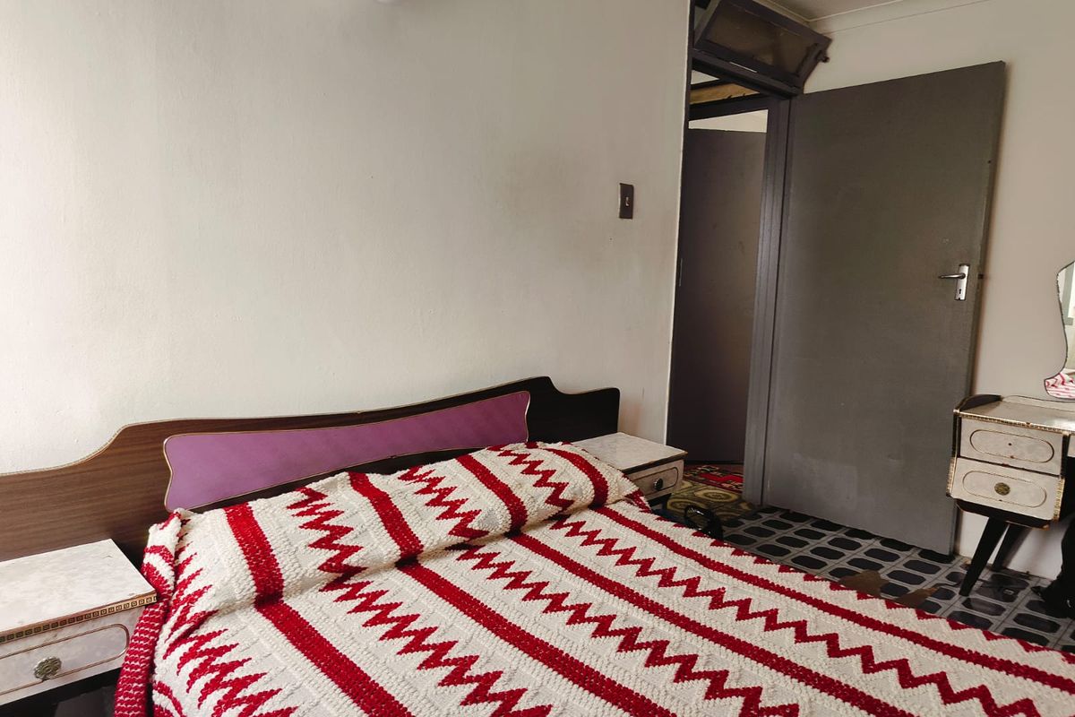 A bedroom featuring dated flooring and a standard interior door, providing a functional space with potential for modernization.