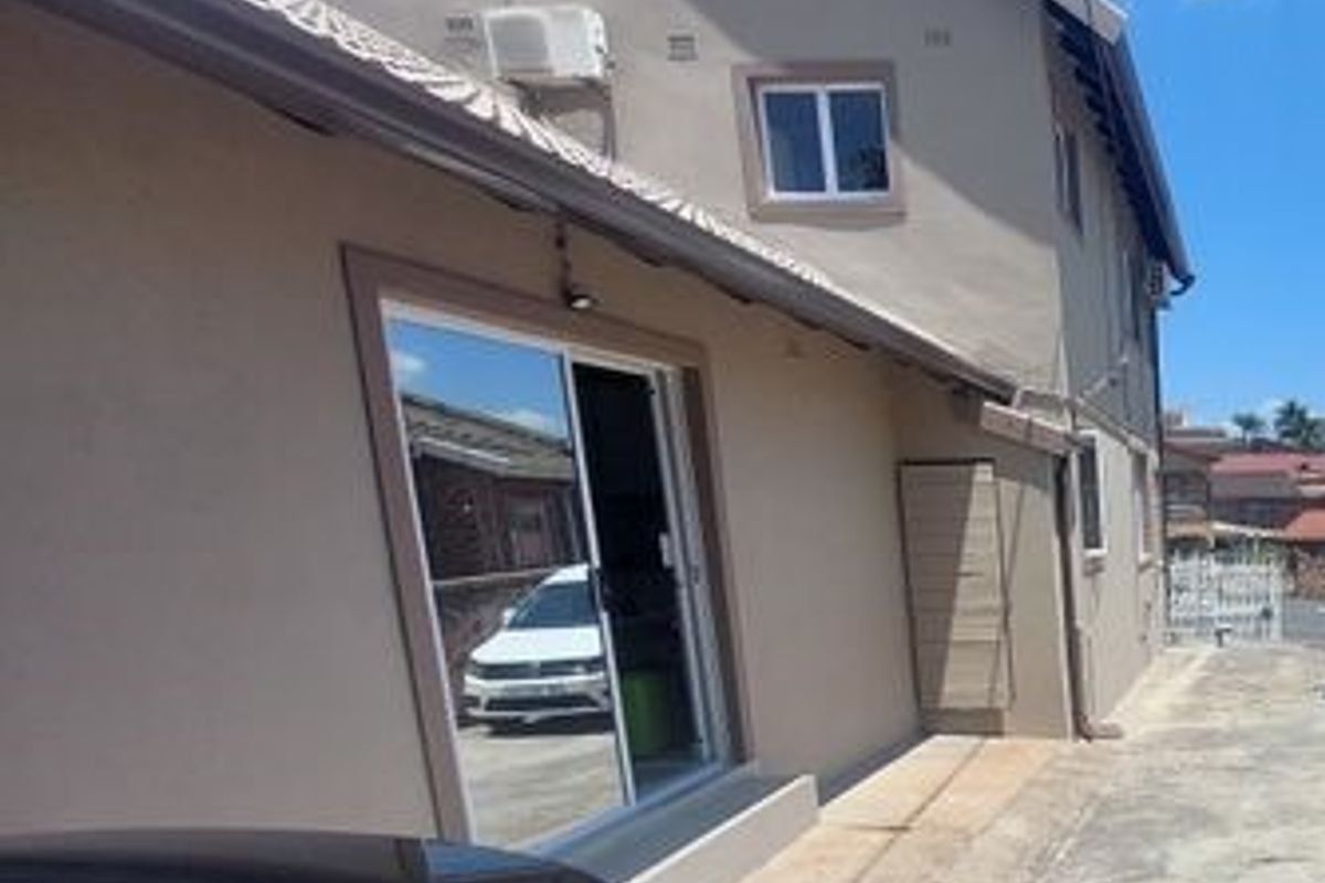 Side exterior view of the house featuring a sliding glass door, wall-mounted air conditioning unit, and concrete pathway.