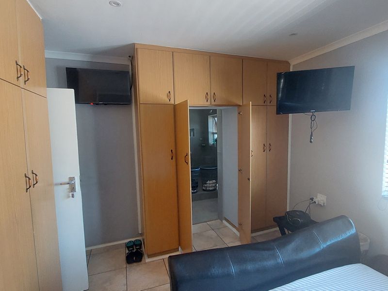 Bedroom featuring extensive built-in wooden cabinetry, tiled flooring, and direct access to an adjoining room.