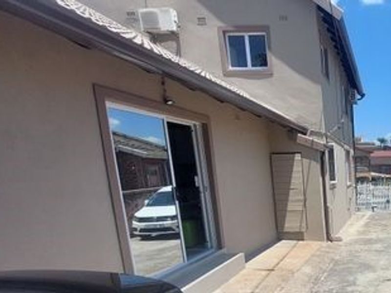 Side view of the property showing a sliding glass door, exterior wall finish, and concrete paving along the building perimeter.
