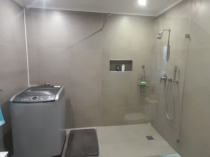 Modern bathroom featuring a spacious walk-in shower with a glass screen, tiled walls, and a convenient recessed wall niche for storage.