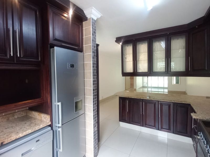 A well-maintained kitchen featuring dark wood cabinetry, granite countertops, and built-in appliances, offering a classic and functional culinary space.
