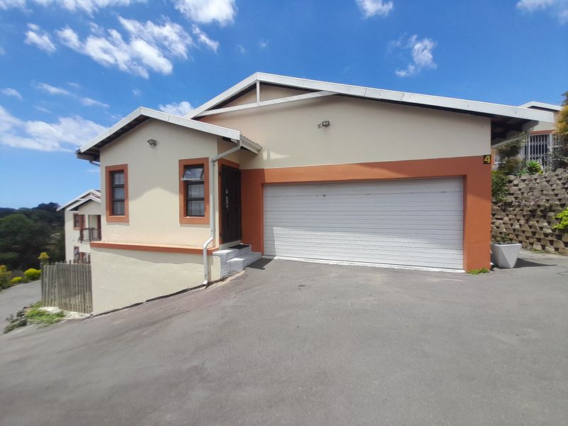 Front exterior view of a cluster home featuring a single garage, paved driveway, and a pitched roof design.