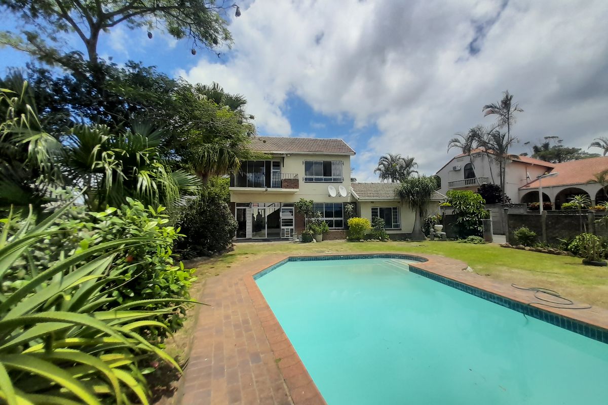 Rear view of the cluster property featuring a swimming pool, paved surround, and established garden area with a two-story building facade.