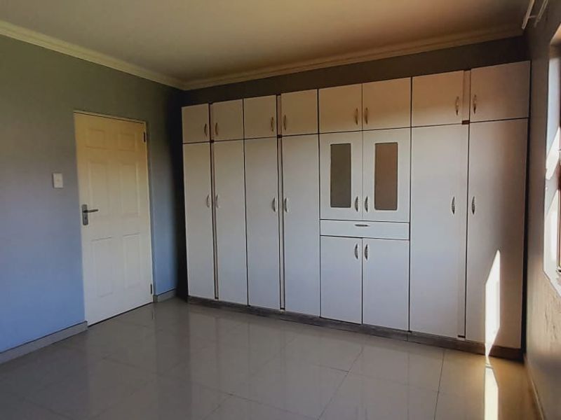 A bright bedroom featuring tiled flooring and extensive built-in cabinetry with integrated storage and shelving.