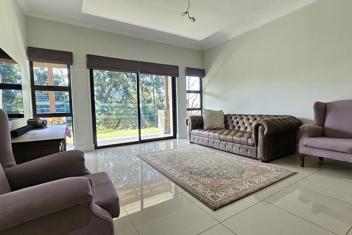 A bright living room featuring large sliding glass doors that provide access to the outdoor area, complemented by polished floor tiles and recessed ceiling detail.