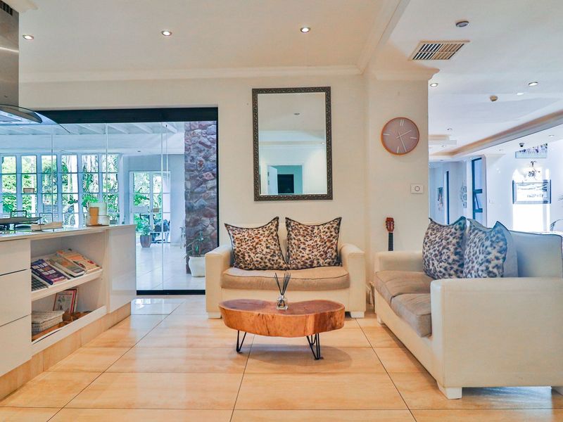 Spacious open-plan living area featuring modern tiled flooring, recessed lighting, and seamless flow to an outdoor patio through large sliding glass doors.