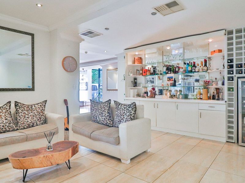 A well-appointed home bar area featuring custom built-in cabinetry, integrated wine storage, glass shelving, and polished tiled flooring.