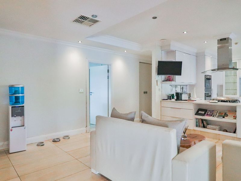 Modern open-plan living area featuring a sleek kitchen with built-in cabinetry, stainless steel extractor fan, and tiled flooring throughout.