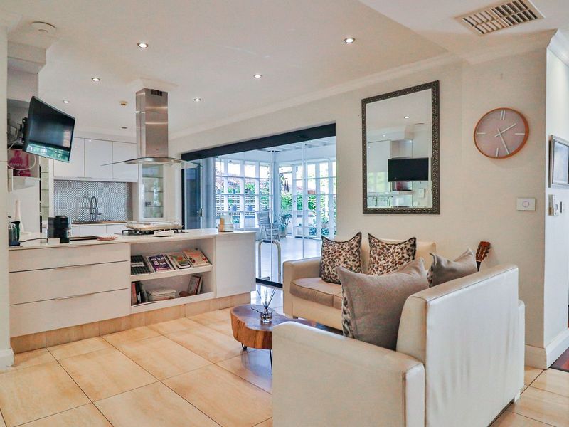 Spacious open-plan living area featuring a modern kitchen with island, sleek cabinetry, and seamless flow to an enclosed patio through large sliding glass doors.