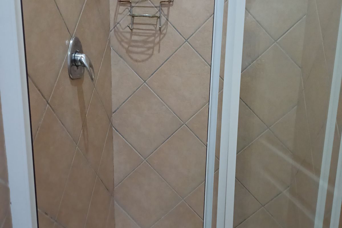 A functional shower enclosure featuring tiled walls, a glass door, and a built-in shower mixer.