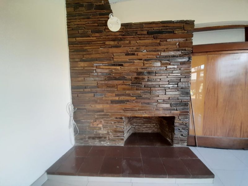 A living room area featuring a prominent stone fireplace with a tiled hearth and a wooden door.