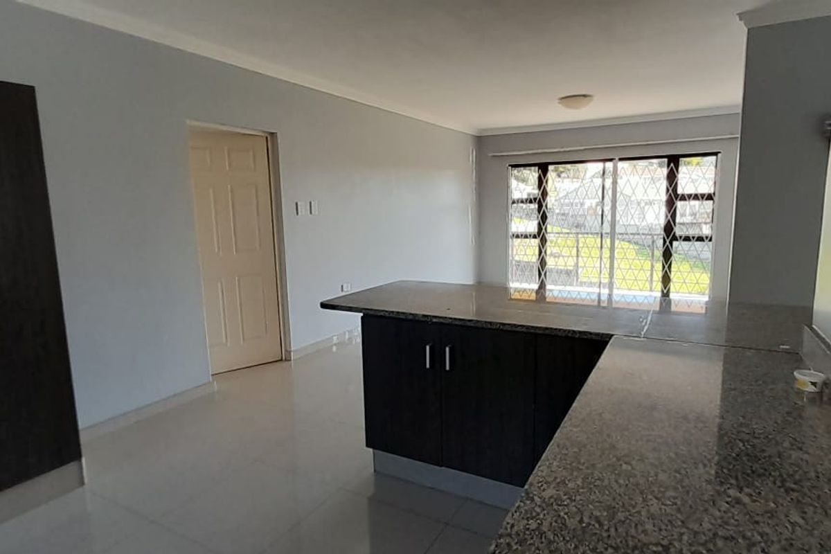 Spacious open-plan living area featuring tiled flooring, granite kitchen countertops, and built-in cabinetry, offering a clean and functional layout.