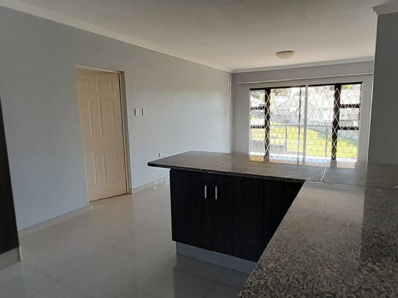 Spacious open-plan living area featuring tiled flooring, granite kitchen countertops, and built-in cabinetry, offering a clean and functional layout.
