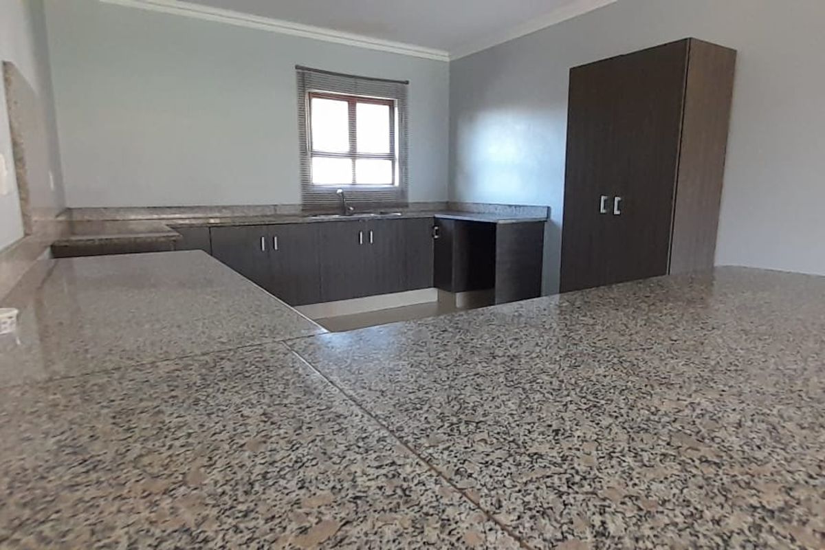 A functional kitchen featuring granite countertops, ample built-in cabinetry, and a window providing natural light.