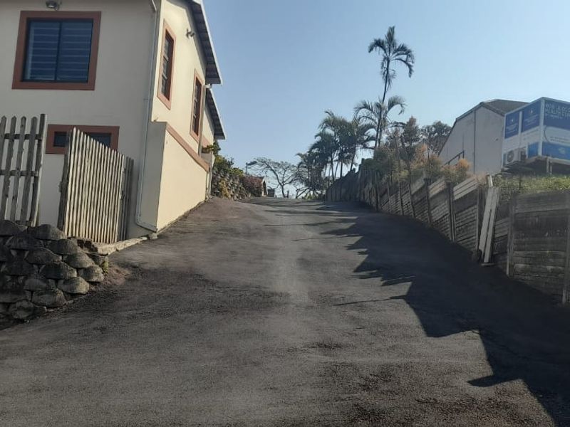 View of the property driveway and exterior boundary features, including retaining walls and fencing leading up to the townhouse entrance.