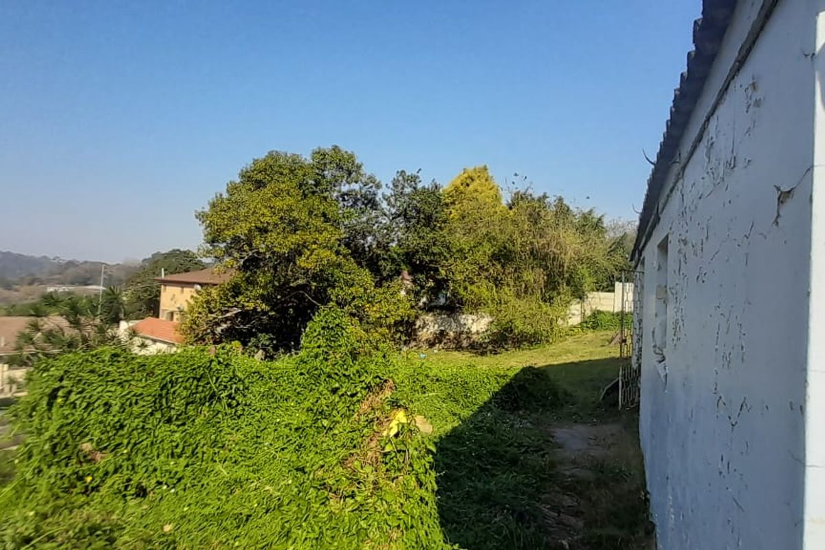 Rear exterior view of the townhouse showing significant wear to the exterior wall finish and overgrown garden area.