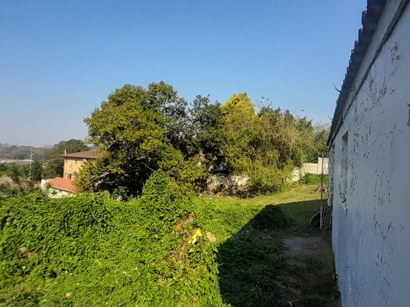 Rear exterior view of the townhouse showing significant wear to the exterior wall finish and overgrown garden area.