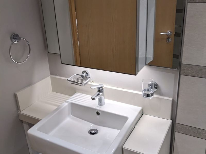 A modern bathroom vanity featuring a white ceramic basin, chrome mixer tap, and integrated mirror cabinet with built-in lighting.