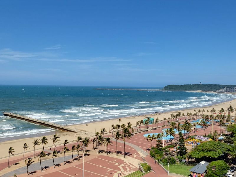 Elevated coastal view overlooking the beach, promenade, and ocean pier.