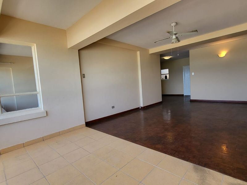 Spacious open-plan living area featuring a mix of tiled and parquet flooring, ceiling fan, and neutral wall finishes.