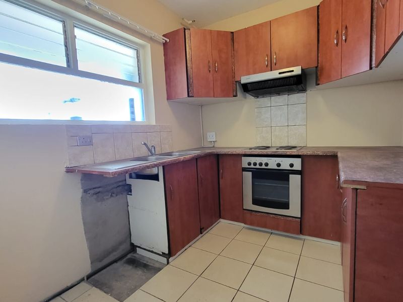 A functional kitchen featuring laminate cabinetry, built-in oven, hob, and extractor fan, with tiled flooring and splashback. Requires minor repairs to base cabinetry.