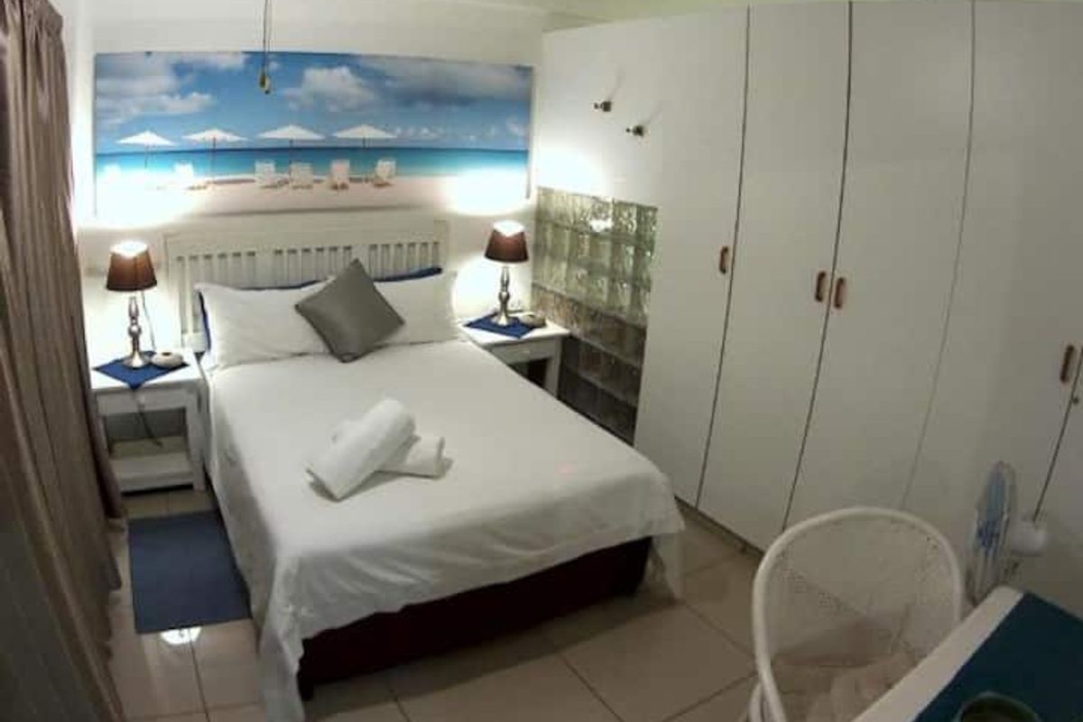 A bedroom featuring built-in floor-to-ceiling wardrobes and a glass block feature wall, finished with neutral floor tiles.