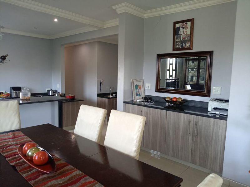 Open-plan dining and kitchen area featuring modern built-in cabinetry, granite countertops, and neutral finishes, creating a functional and connected living space.