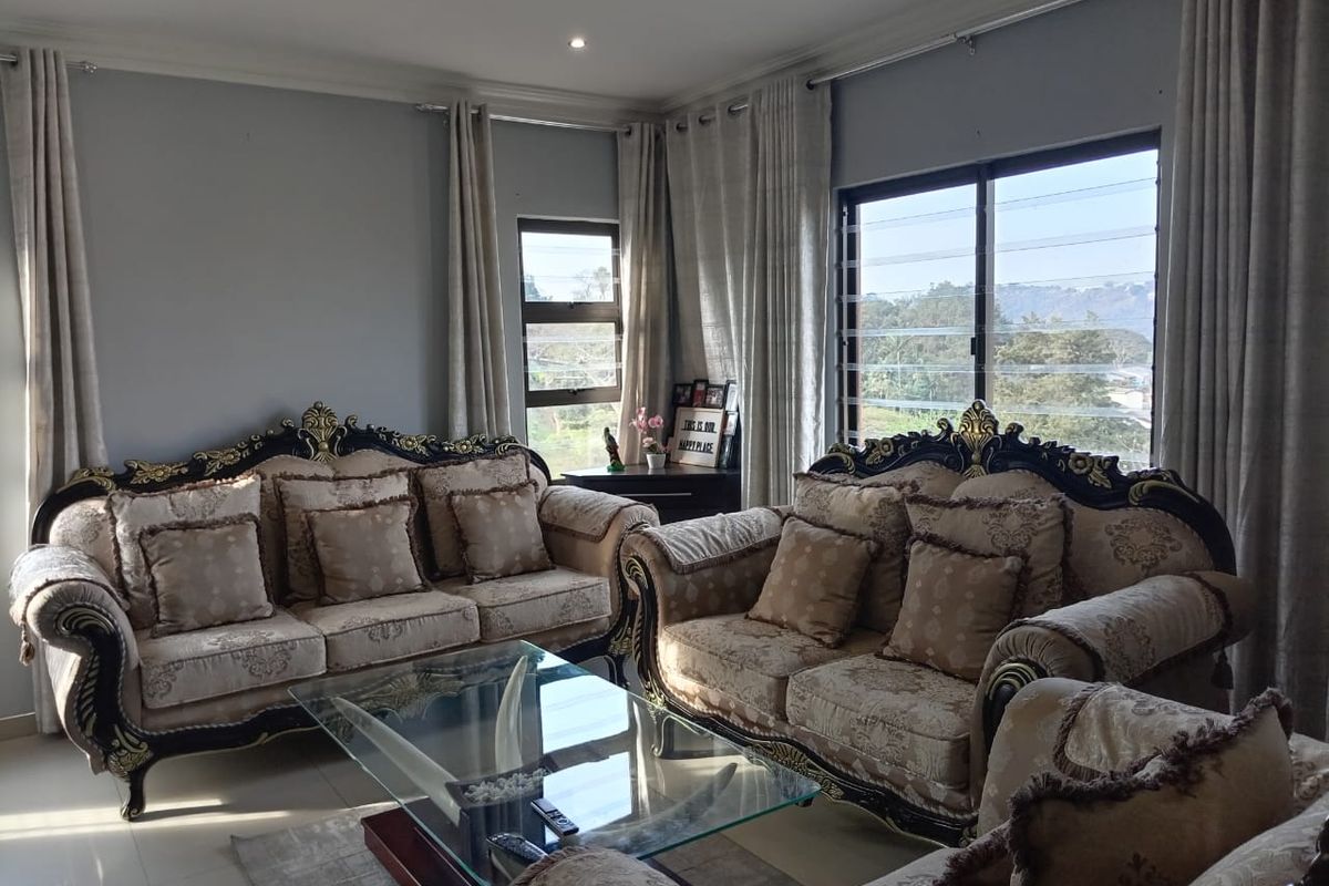 A well-maintained living room featuring tiled flooring, crown molding, and large louvered windows that provide natural light and scenic views.