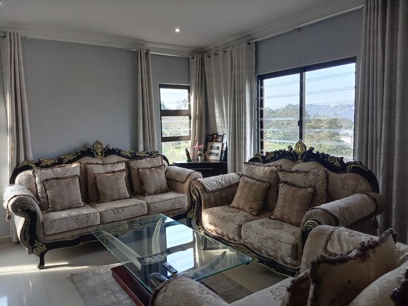 A well-maintained living room featuring tiled flooring, crown molding, and large louvered windows that provide natural light and scenic views.