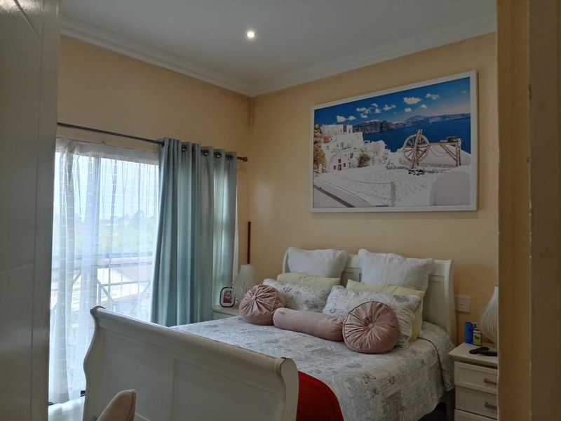A bedroom featuring a sliding glass door with curtains, recessed downlighting, and decorative cornice detailing.