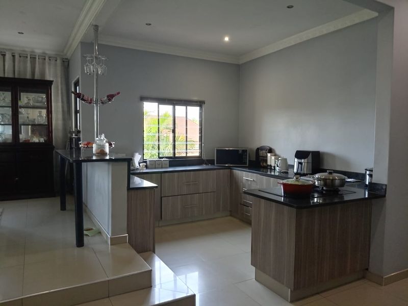 Modern kitchen featuring wood-finish cabinetry, dark granite countertops, a breakfast bar, and tiled flooring, offering a functional and well-maintained cooking space.