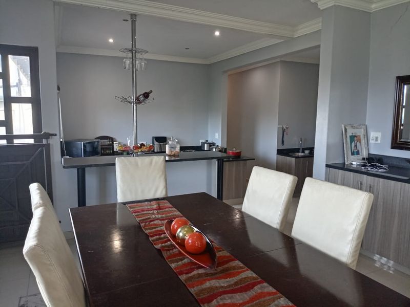 Open plan dining and kitchen area featuring built-in cabinetry, granite countertops, and a breakfast bar, with neutral wall finishes and recessed lighting.