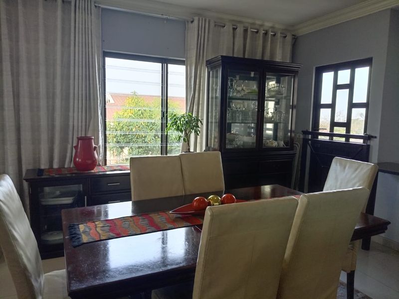 A dining room featuring crown molding and natural light from a sliding window and a decorative window.