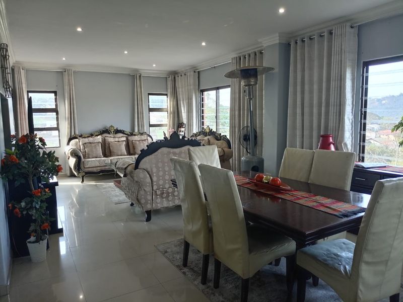 Spacious open-plan living and dining area featuring tiled flooring, recessed downlighting, and large windows that provide ample natural light.