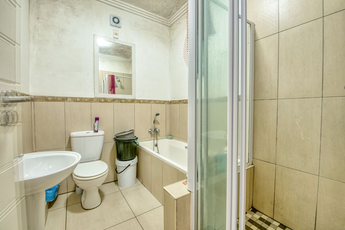 A compact bathroom featuring a pedestal basin, toilet, and a combined shower and bathtub unit with tiled walls.