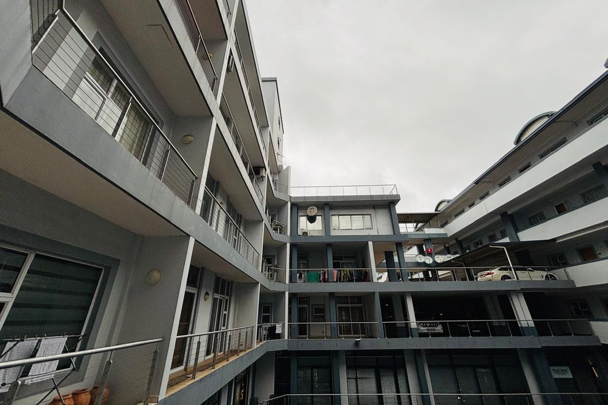 A low-angle view of a multi-story apartment complex featuring stacked balconies with stainless steel railings and integrated parking levels.