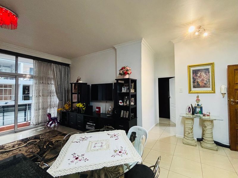 Open-plan living and dining area featuring tiled flooring, coving, and a large sliding glass door providing access to the balcony.
