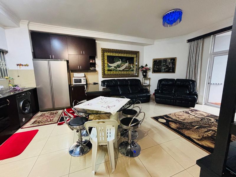 Open-plan living and kitchen area featuring tiled flooring, dark cabinetry, and direct access to an outdoor space through a sliding glass door.