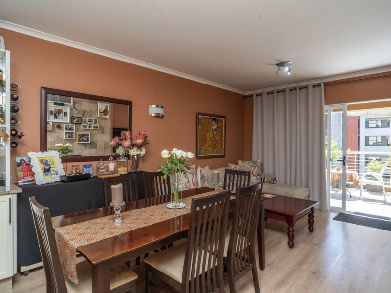 Open-plan living and dining area featuring laminate flooring, a built-in display cabinet, and direct access to a private balcony through sliding glass doors.