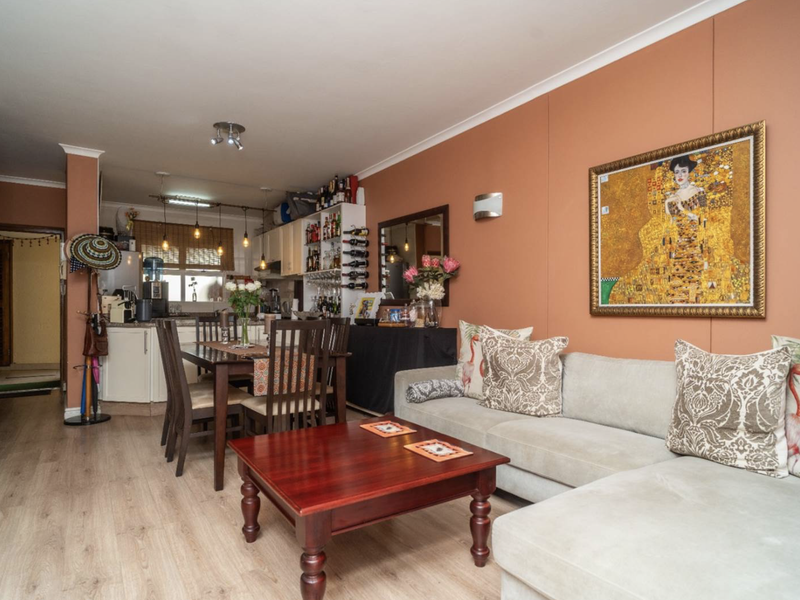 Open-plan living and dining area featuring laminate flooring and an integrated kitchen space with built-in cabinetry.