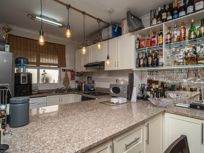 A functional kitchen featuring granite countertops, ample built-in cabinetry, an integrated extractor fan, and dedicated glass shelving for display.