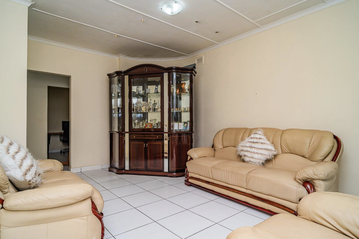 A living room featuring tiled flooring and a panelled ceiling, offering a functional space that could benefit from modern updates and cosmetic improvements.