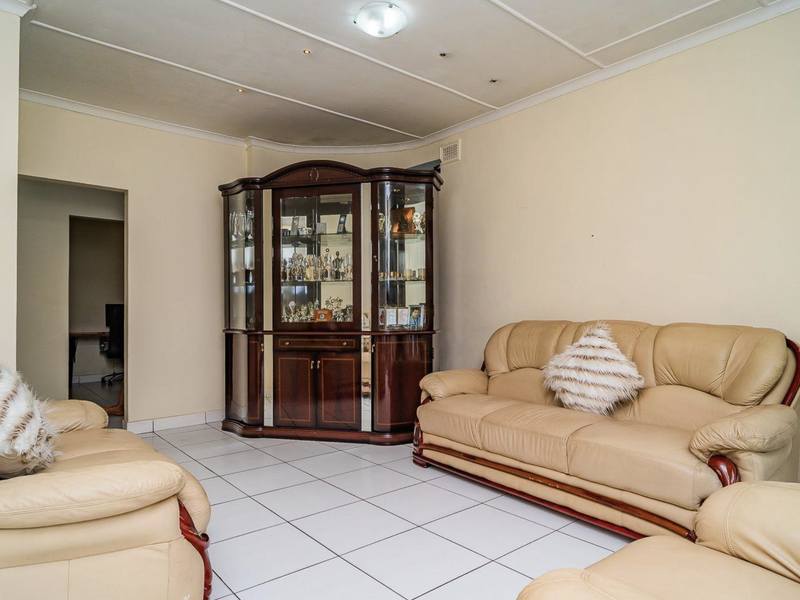 A living room featuring tiled flooring and a panelled ceiling, offering a functional space that could benefit from modern updates and cosmetic improvements.