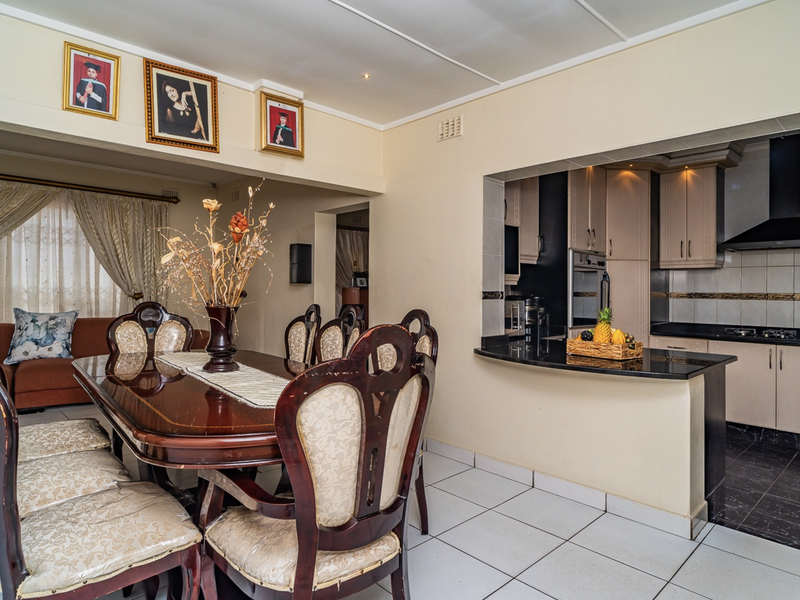 Open-plan dining area adjacent to a functional kitchen featuring built-in cabinetry, granite countertops, and integrated appliances.