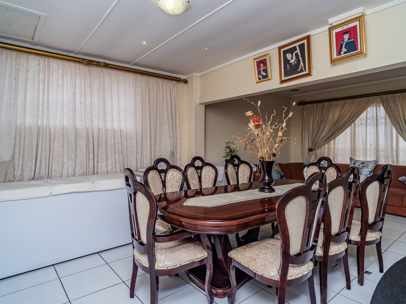 A spacious dining area featuring tiled flooring and neutral walls, providing a functional space for family meals and gatherings.